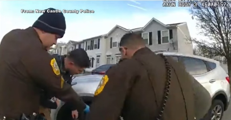 a group of police officers from the new castle county police trying to lift a car off a 70 year old woman as seen from a body cam