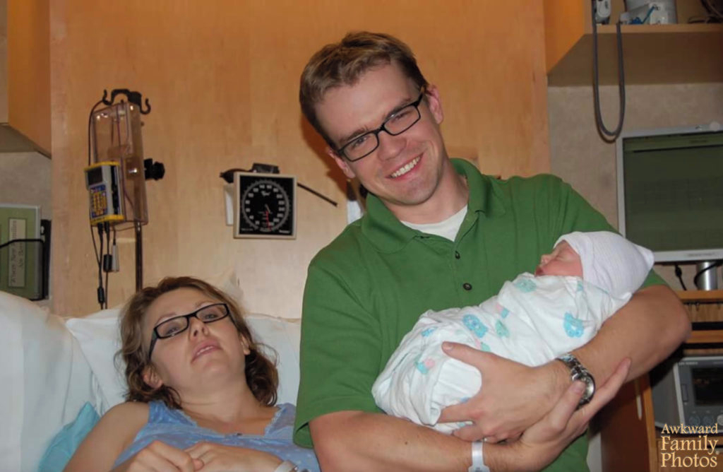exhausted mom and dad pose with new baby