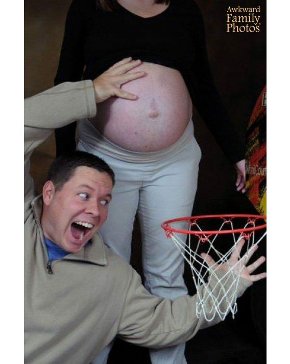 man pretending to dunk his pregnant wife's belly in basketball net