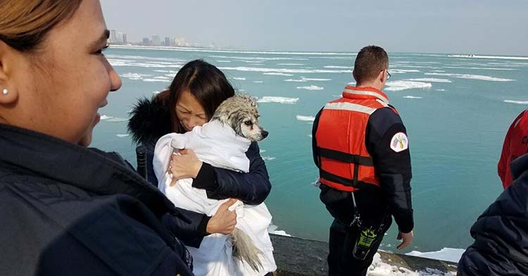 woman hugging dog next to icy lake