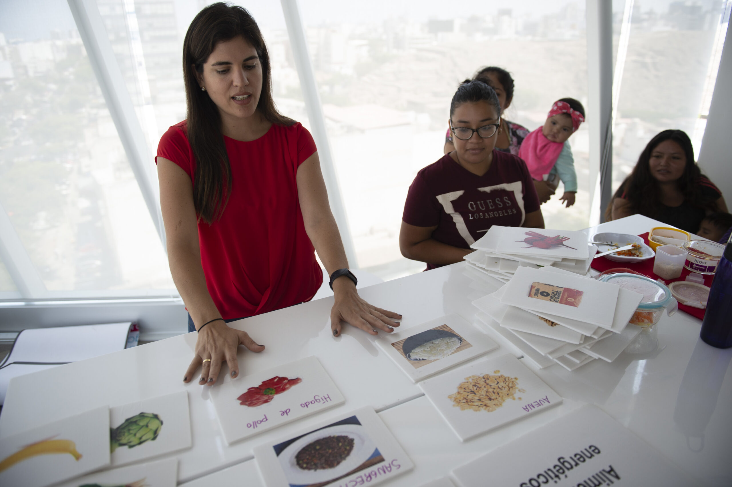 a woman named adriana zavalaga teaching women using photos of food on a table how to give their children with clefts the nutritious food they need