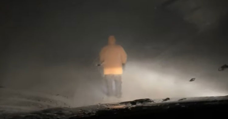 80-year-old walking ahead of car through blizzard