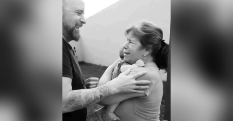 black and white photo of a man smiling as his blind mom cries and hold her grandchild for the first time