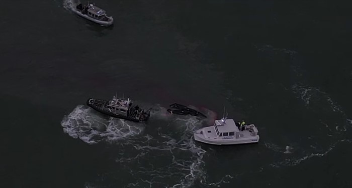 three rescue boats on the water off the massachusetts coast approaching three fishermen whose boat overturned