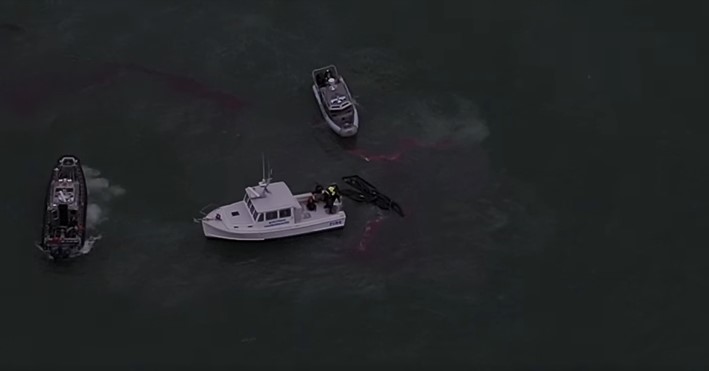 three rescue boats on the water off the massachusetts coast, one of which is rescuing three fishermen from the fridgid water