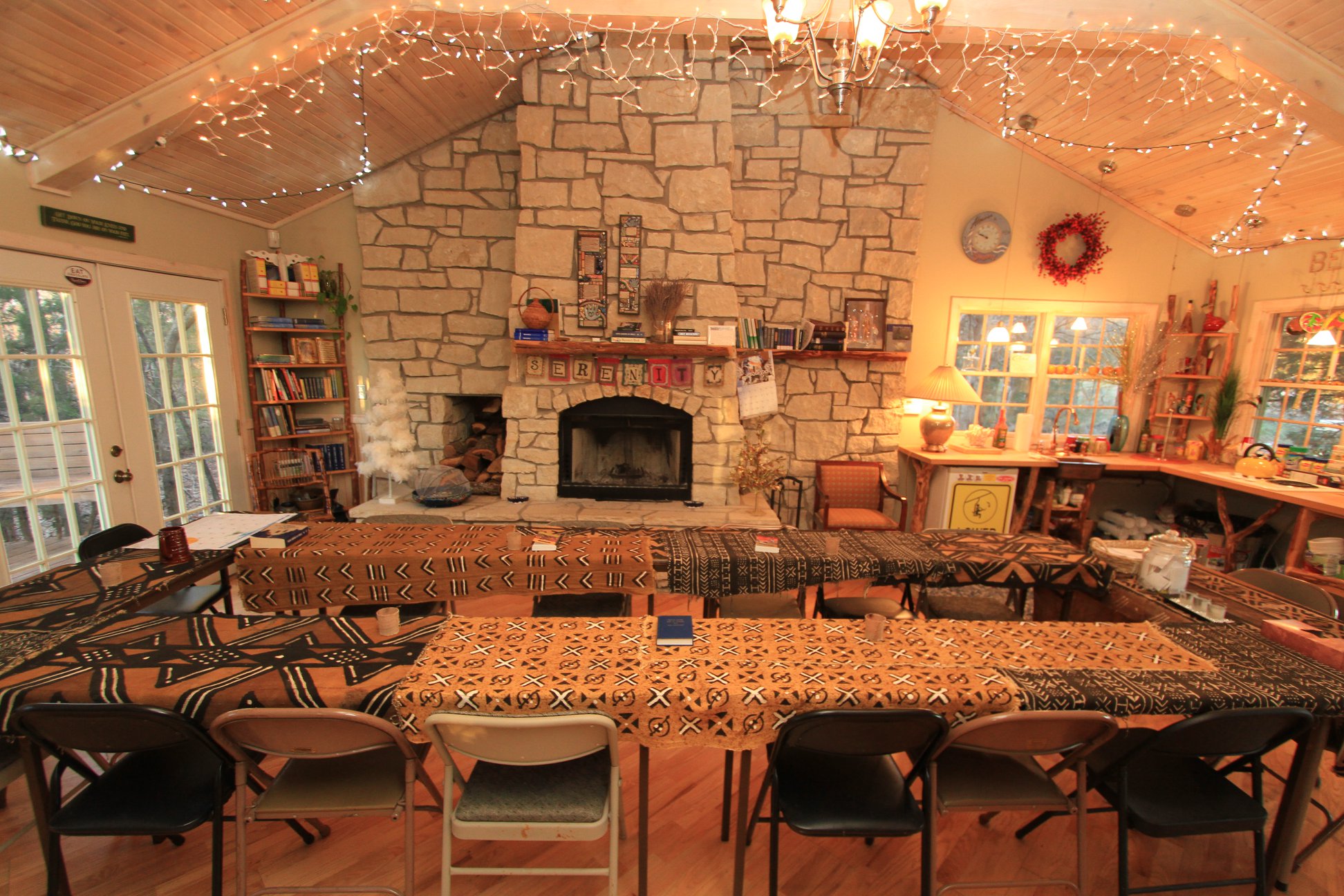 interior of a building with a stone fireplace and several tables and chairs as part of cedar home in kansas