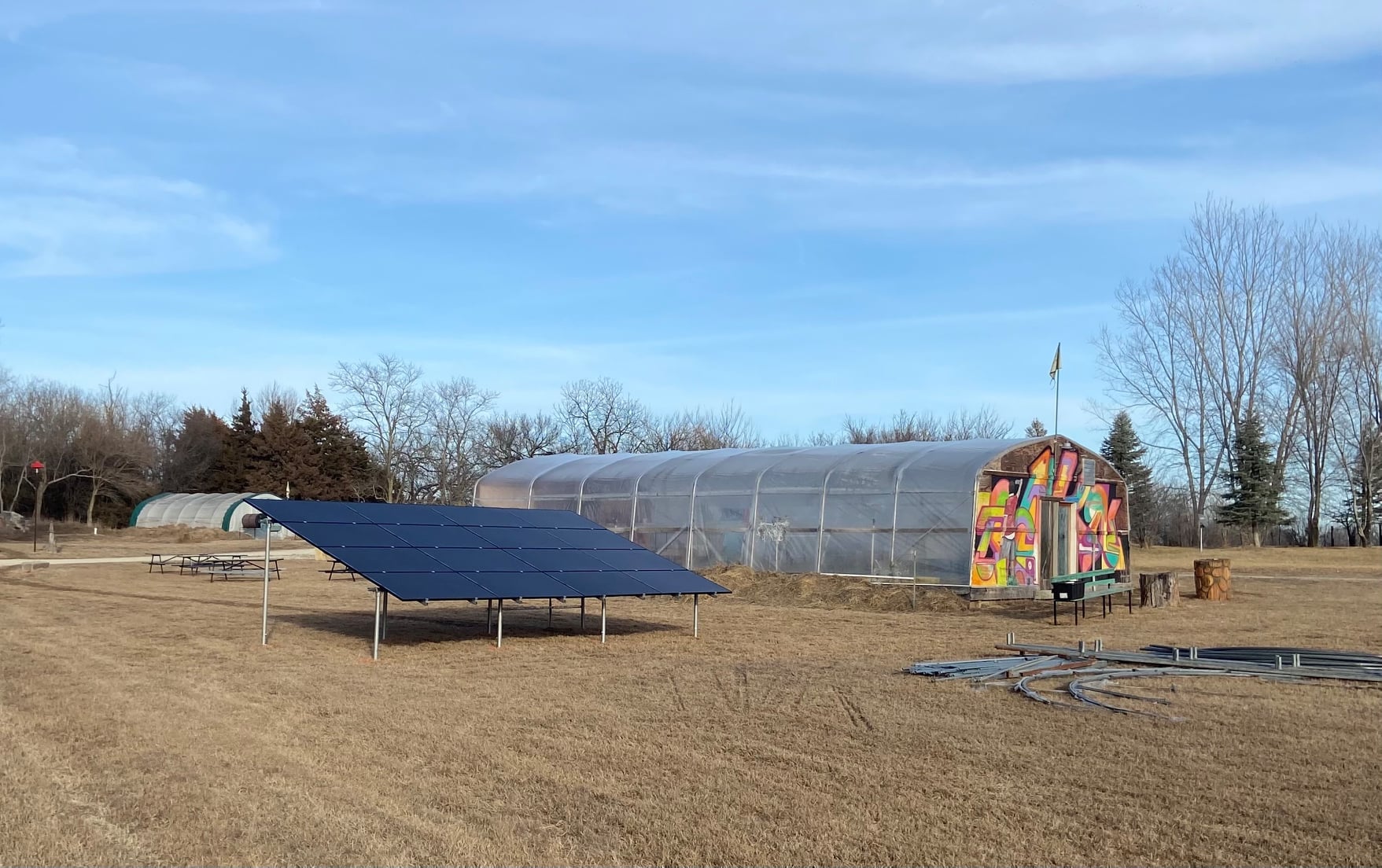 a large greenhouse decorated in graffiti and large solar panels that are located at cedar home in kansas 