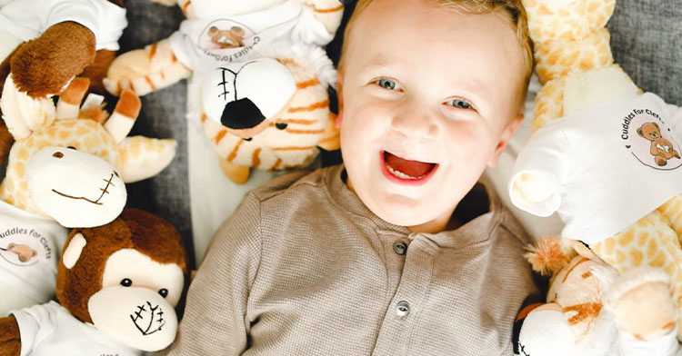 little boy surrounded by stuffed animals with surgery scars
