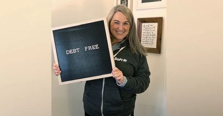 a woman named amanda courtney smiling as she holds up a board that reads "debt free"