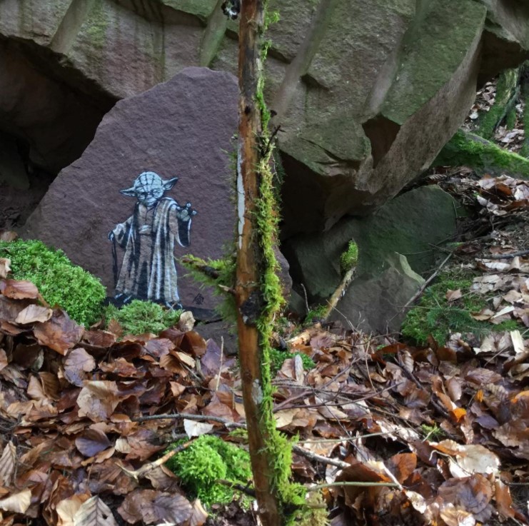graffiti art by jps of a mini yoda on a rock using the force to cause crack in the ground next to him