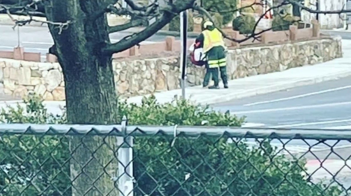 a distant view of a garbage truck driver named mike nance hugging a woman in need on the sidewalk 