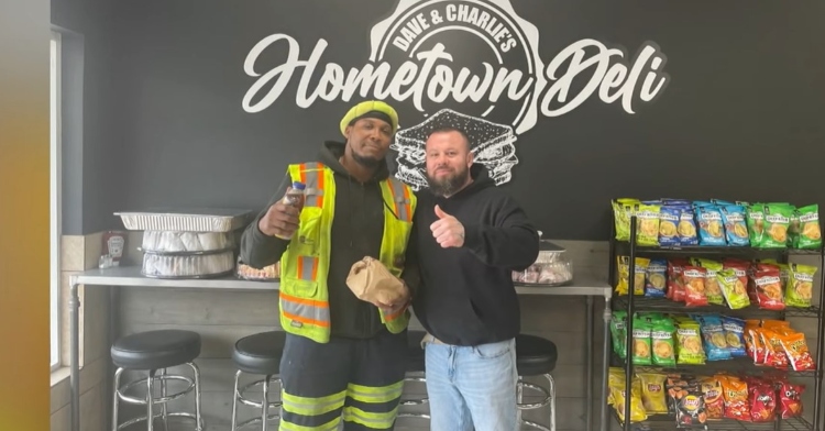 a garbage truck driver named mike nance and one of the restaurant owners of "dave and charlie's hometown deli" posing for a photo in front of the deli's logo