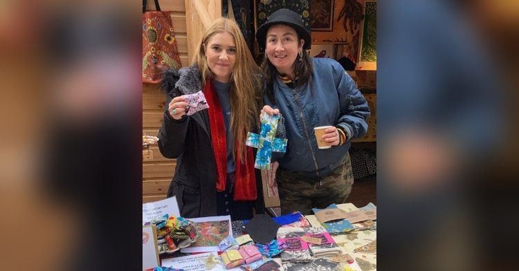 a woman named ella lambert posing with another woman as they hold and show off the reusable pads they have on a table through the pachamama project