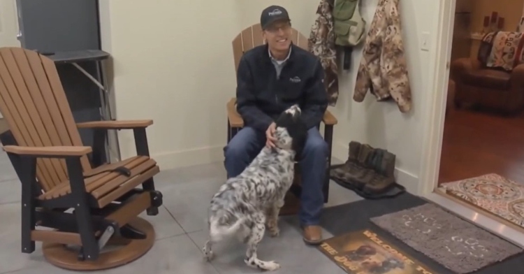 a man named roger jacobs smiling as he sits in a chair and pets his dog named salty