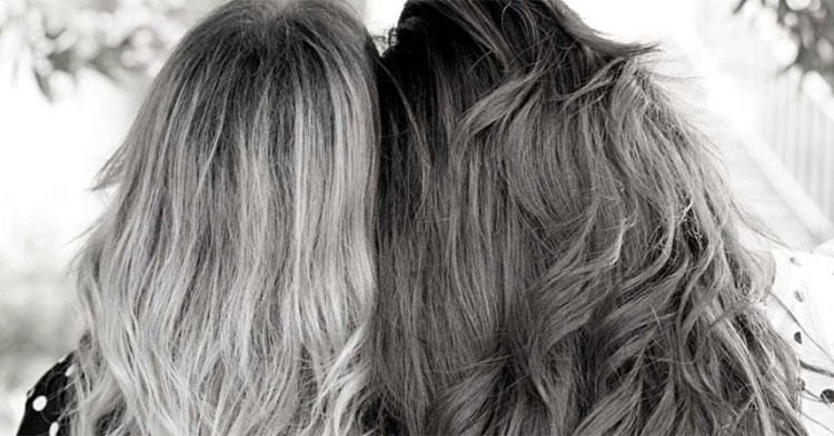 black and white photo of sisters sitting side by side with backs turned to camera