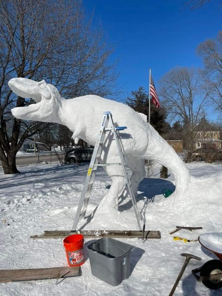 closeup of a 12 foot tall snow sculpture of a t-rex being built by a man named paul larcom in minnesota 