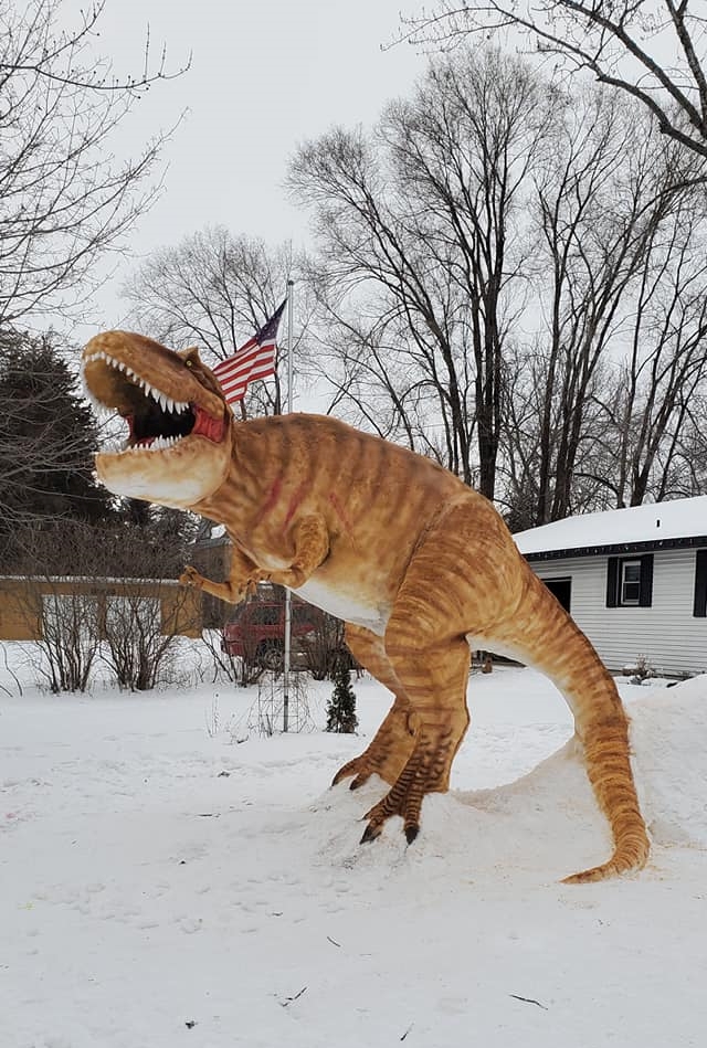 a 12 foot tall snow sculpture of a t-rex made by a man in minnesota named paul larcom