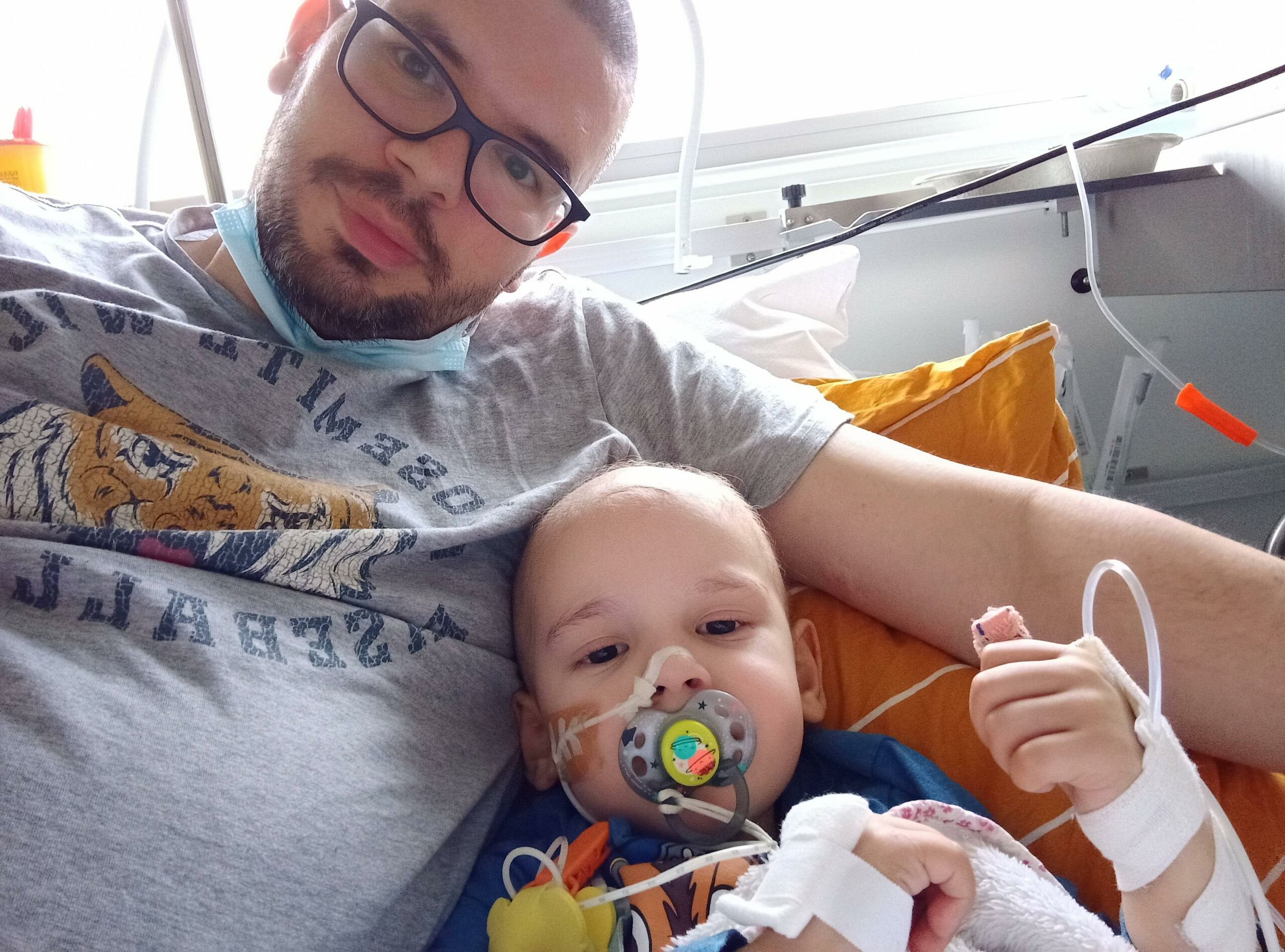 a man posing for a selfie with his three year old son in a hospital who just beat cancer