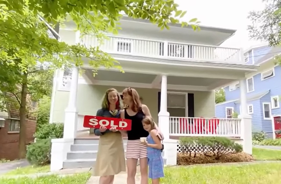 Herrin Hopper and Holly Harper holding a "sold" sign outside a house