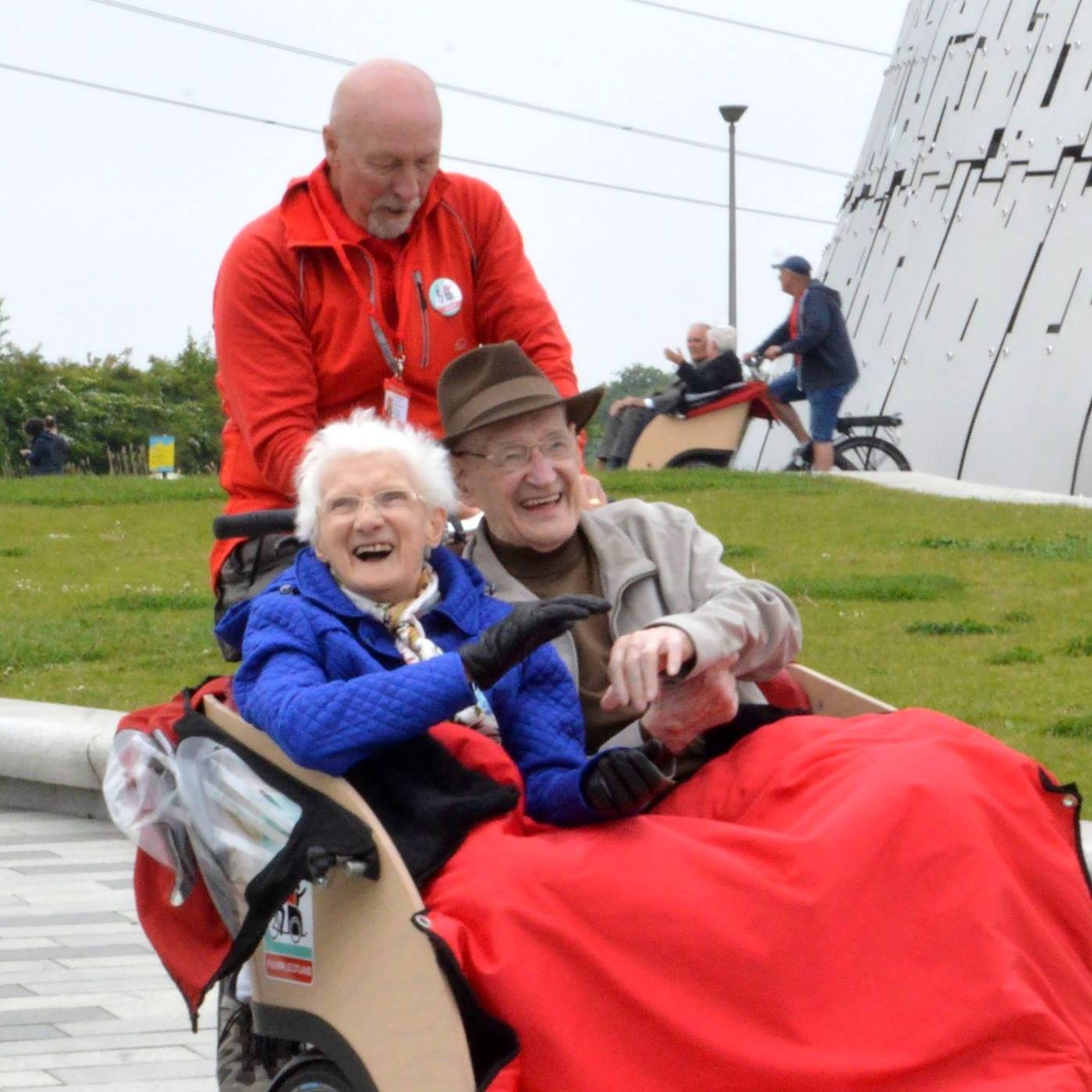 an elderly man and woman smiling together as they ride on a trishaw through the nonprofit cycling without age