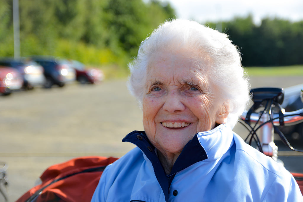 closeup of an elderly woman smiling as she sits on a trishaw through the nonprofit cycling without age