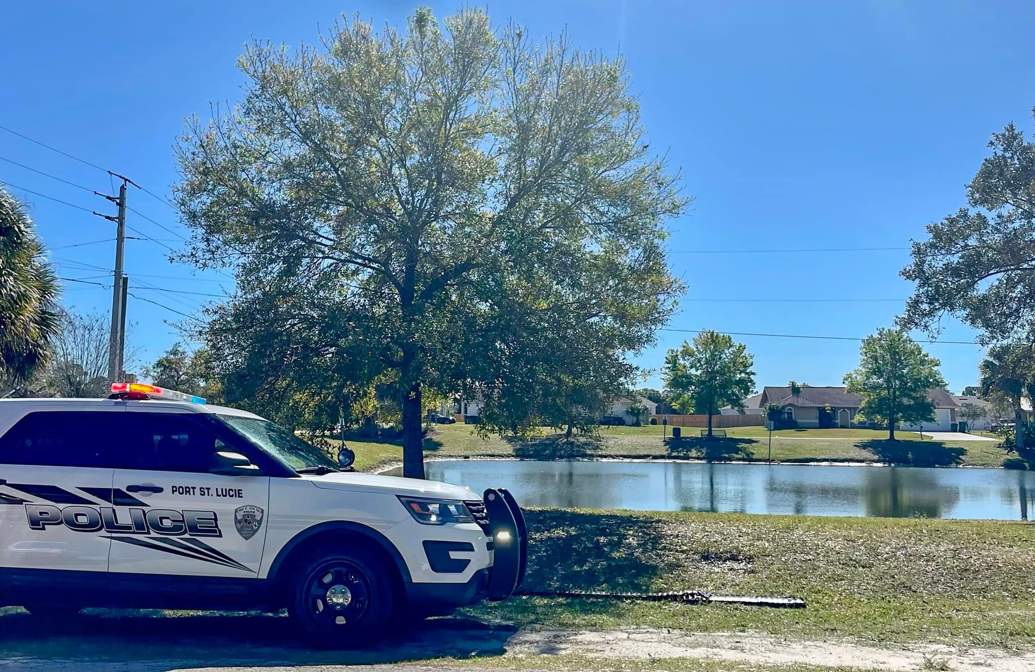 a port st. lucie police department car parked in front of a lake that an 81 year old man named harry smith fell into