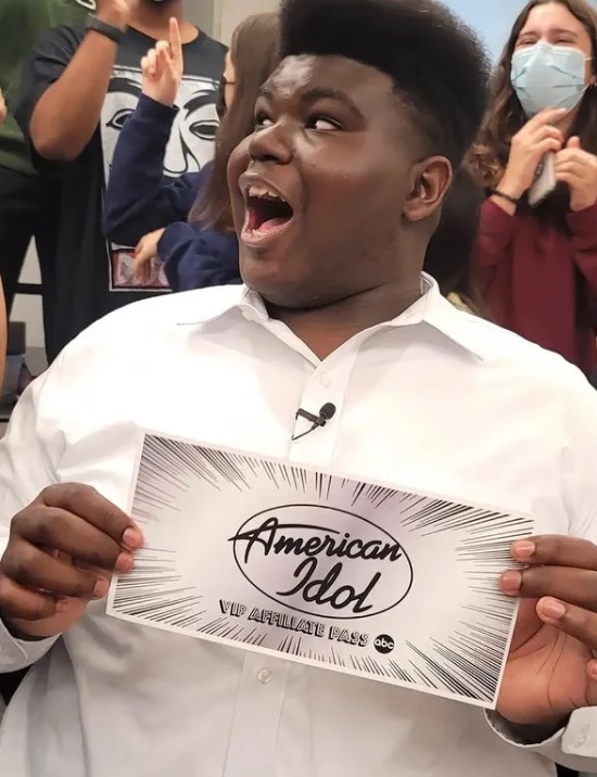 18-year-old douglas mills looking shocked with his classmates as he hold the "american idol: vip affiliate pass" that he won 