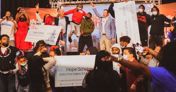 a group of high schoolers celebrating both on and off stage in their auditorium after finding out they can go to college for free through the organization hope chicago