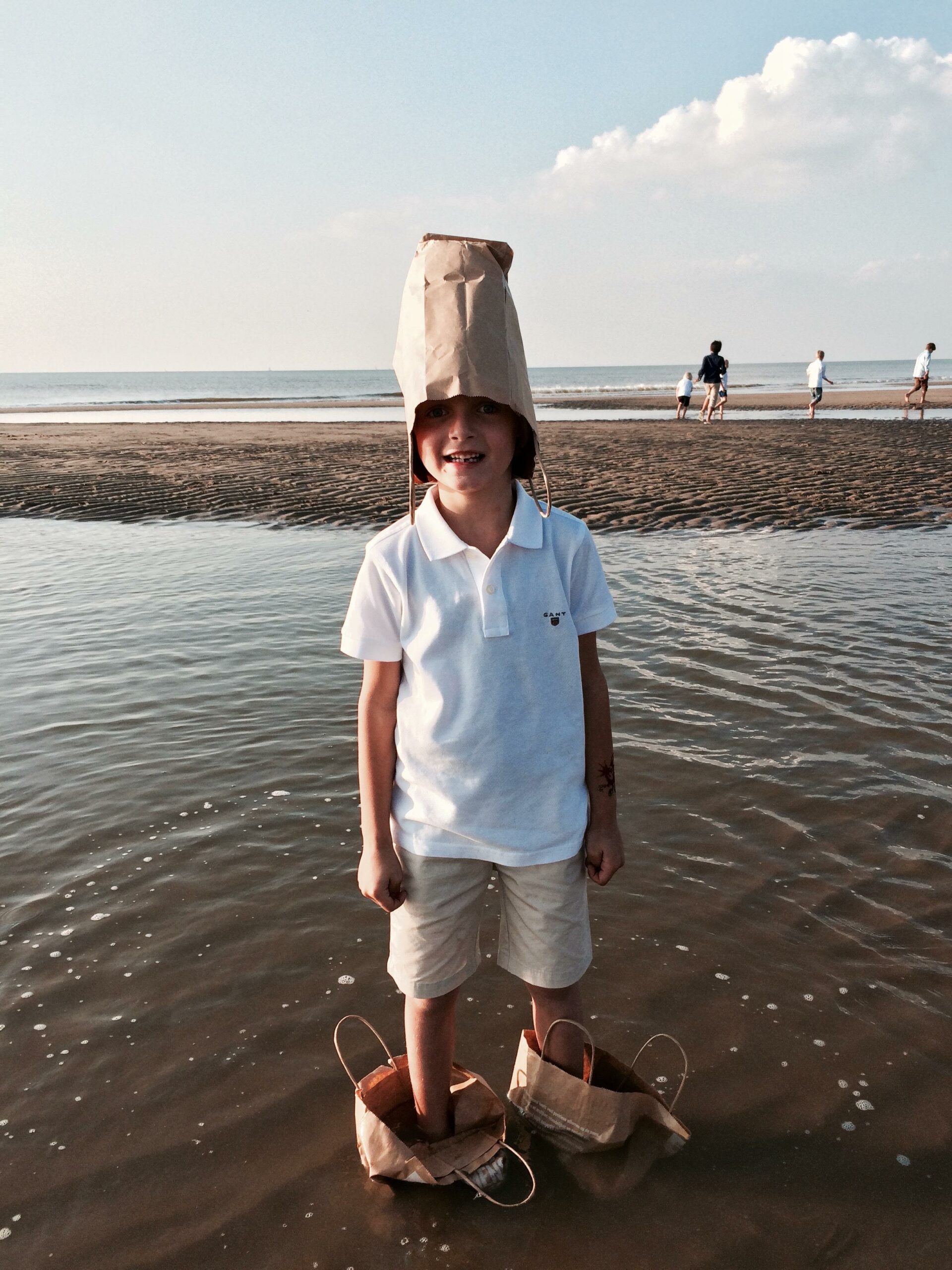 kid with paper bags on feet in ocean