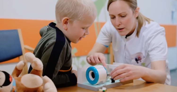 a little boy and a medical professional playing with a miniature lego mri scanner