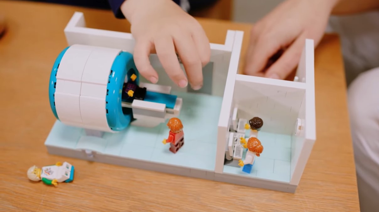 closeup of a kid playing with a miniature lego mri scanner 