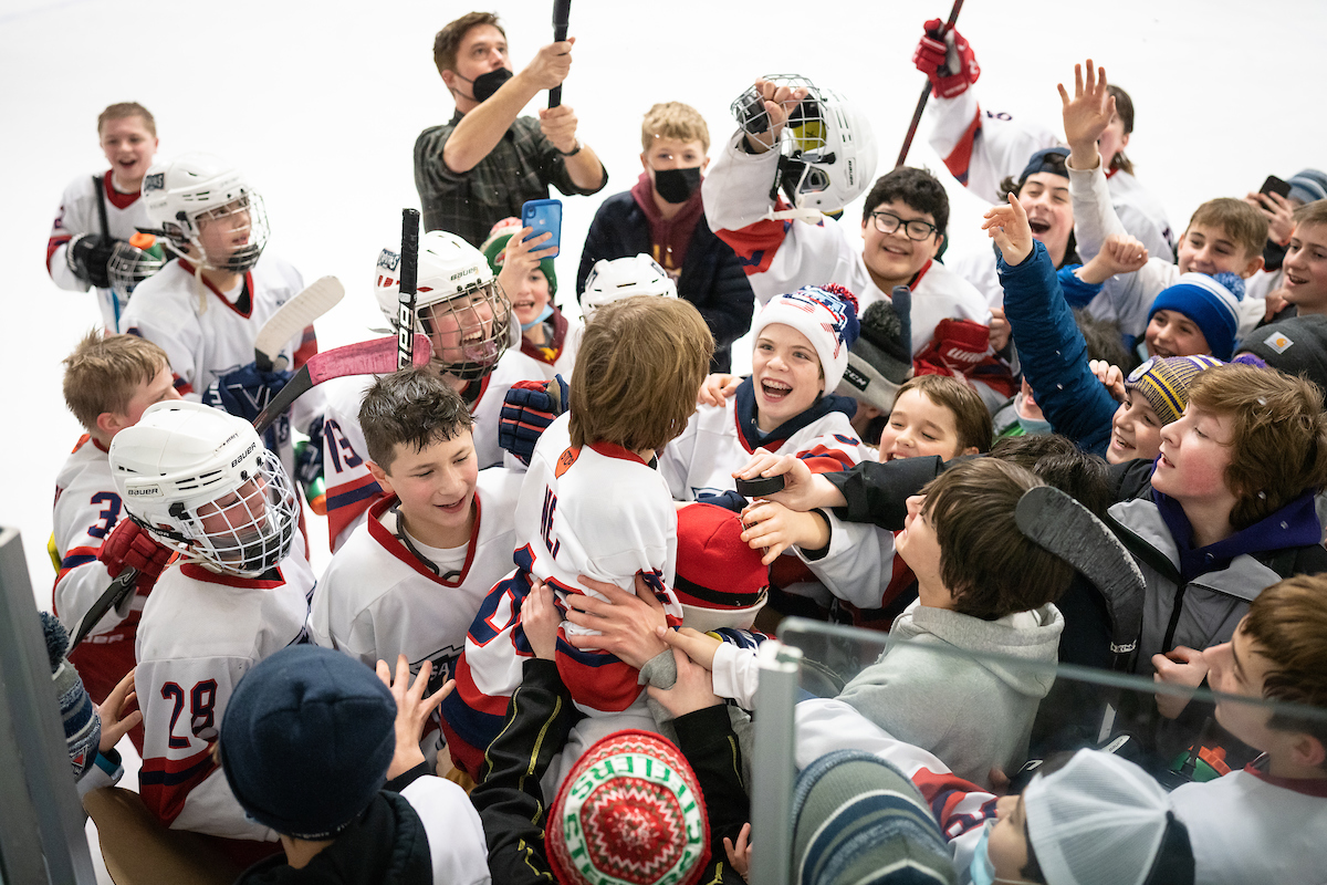 players of the st. paul capitals pee wee team chering as they lift up one of their teammates, owen nei, who just played his last home game