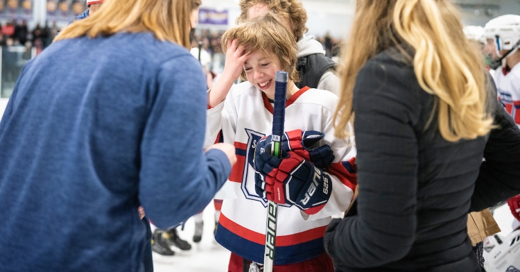 13-year-old owen nei smiling as he's presented with surprises after his last home game with the st. paul capitals