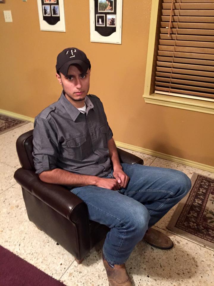 an adult man staring at the camera as he sits on a child-size faux leather chair