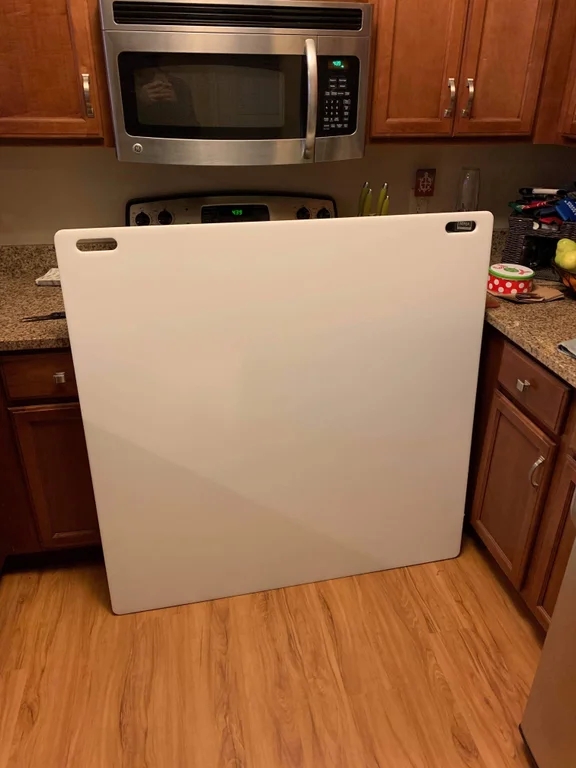 an xxxxl cutting board placed against a stove and, in doing so, almost covers it completely