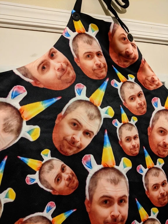 closeup of an apron with a black background and several images of the head of a man who is wearing a unicorn headband