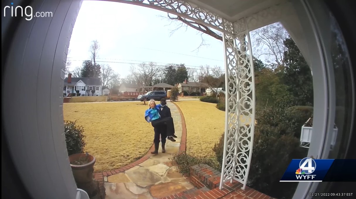 screenshot of ring doorbell camera footage of a man named fred austin carrying an elderly woman to her home after she fell