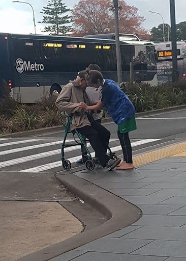 two 13-year-old boys helping an elderly man cross the street with his walker in aukland, new zealand 