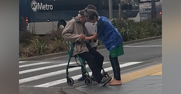two 13-year-old boys helping an elderly man cross the street with his walker in aukland, new zealand