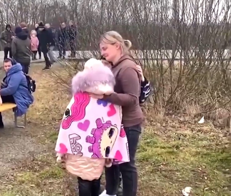 a woman named anna semuk hugging her little boy and girl after reuniting just over the hungarian border 