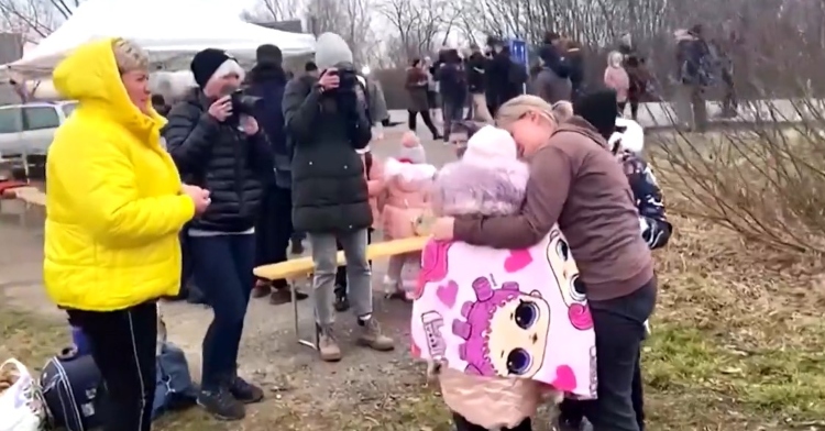 a woman named anna semyuk hugs her two young children after reuniting with them while people with cameras and a woman named nataliya ableyeva watch