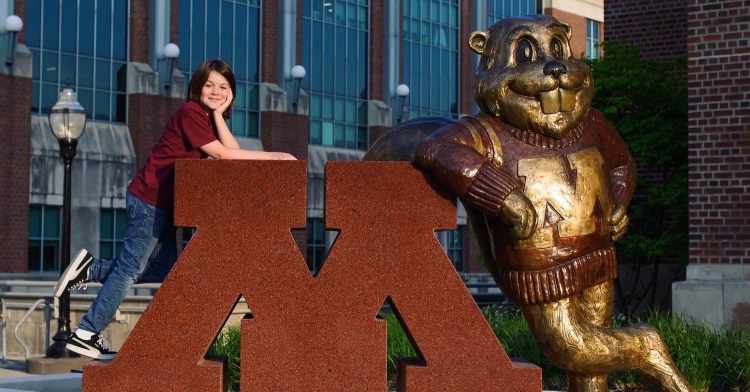 elliott tanner posing for a picture on top of the University of Minnesota's statue
