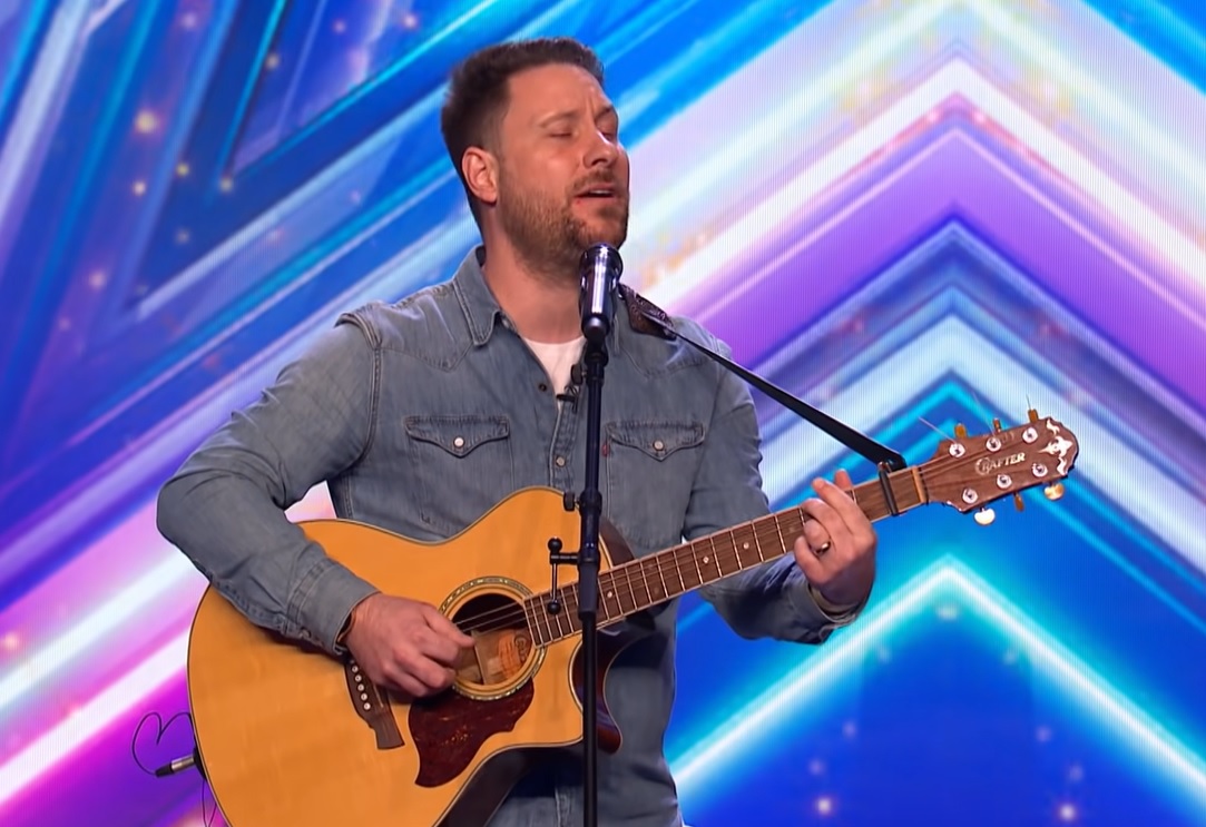 nick edwards singing and playing the guitar on the bgt stage.