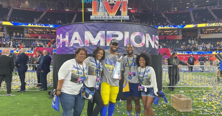 terrell burgess posing with his family on the football field after winning the 2022 super bowl with the los angeles rams.