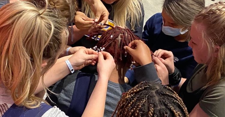 mississippi high schooler, bruce, surrounded by fellow high schoolers who are helping to remove her beads.