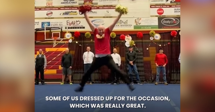 screenshot of a man mid jump as he cheers. he is holding red and gold pompoms in each hand. he is a father of a cheerleader at cedar high school. the image is captioned with “some of us dressed up for the occasion which was really great.”