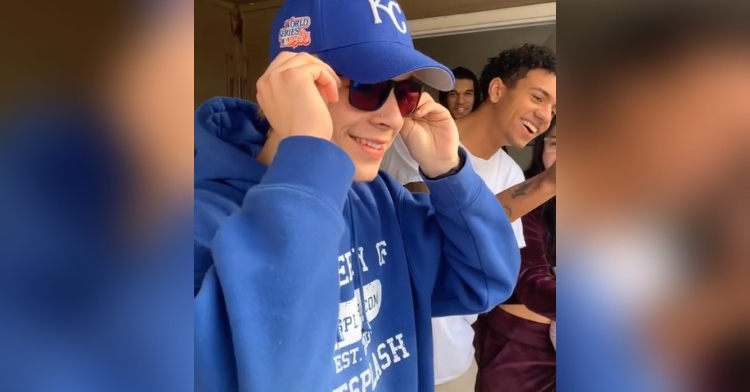 closeup of 19-year-old zane stubbendeck trying on a pair of enchroma colorblind outdoor sunglasses. as zane smiles and looks into the distance, his friends surround him and watch his reaction.