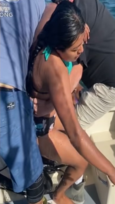 two fishermen helping a 16-year-old onto their boat. she had been floating in the  monterey bay for nearly 30 minutes and is not able to stand without their help.