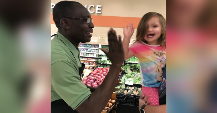 a publix worker named gilnet, also referred to as high five, giving a little girl named fiona a high five