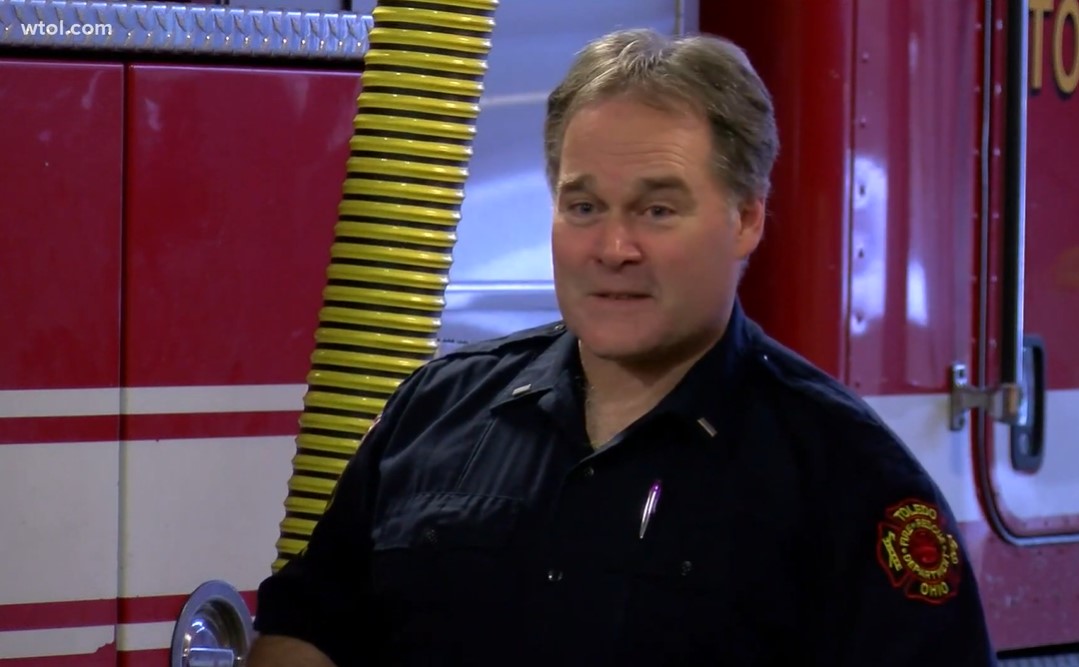 lieutenant jim shulty talking as he stands in front of a firetruck in the toledo fire station.